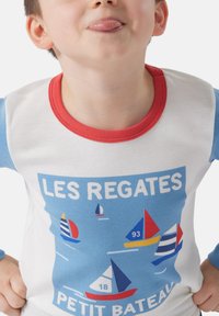 Camicia a maniche lunghe in cotone con scollatura rossa e maniche blu, presenta una stampa grafica azzurra di velieri e il testo "LES REGATES".