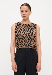 Χακί αμάνικο τοπ με μαύρο λεοπάρ σχέδιο, πλεκτή υφή, στρογγυλή λαιμόκοψη και κοντό σχέδιο, συνδυασμένο με μαύρο παντελόνι ψηλής μέσης.