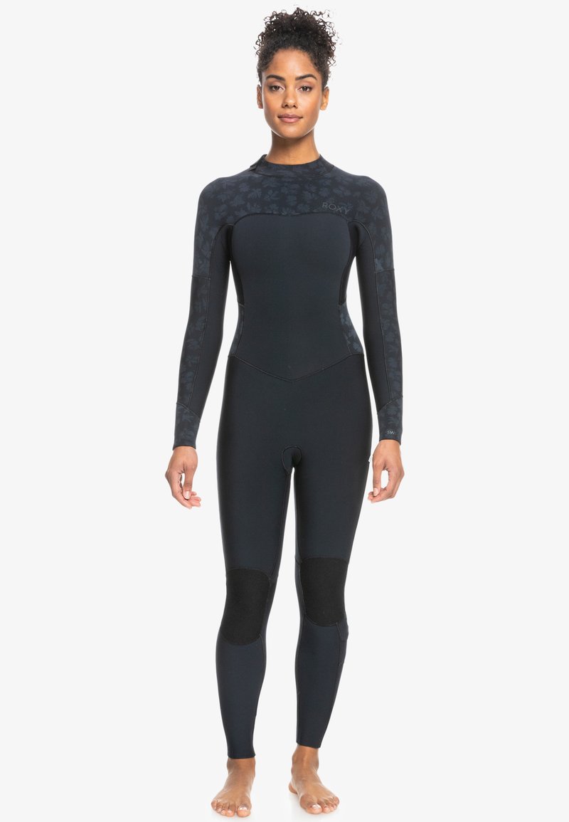 Traje de neopreno negro con un diseño superior texturizado, mangas largas y parches en las rodillas. Fabricado con material flexible para deportes acuáticos.