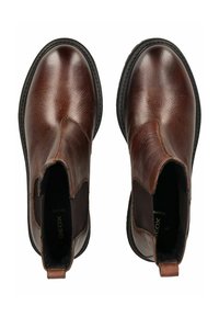 Botas de tobillo de cuero marrón con paneles laterales elásticos, puntera redonda, acabado texturizado y una lengüeta. Presentan una suela de goma negra con costuras.