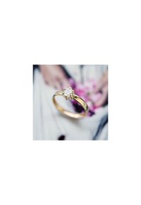 Bague en or avec un centre en diamant rond et transparent, monté sur une monture à six griffes. Anneau lisse avec une finition brillante, au design minimaliste.
