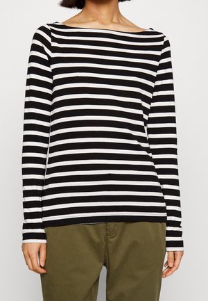 Top de rayas blancas y negras de manga larga con escote barco, hecho de un tejido suave, combinado con pantalones verde olivo.