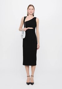 Rochie midi neagră, cu textură în dungi, având un decolteu asimetric și detaliu cu decupaj. Asortată cu o geantă texturată de culoare deschisă.