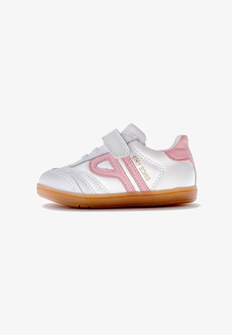 Zapatilla deportiva blanca con detalles en rosa y tira de velcro, con una superficie texturizada, suela de goma y diseño curvado.
