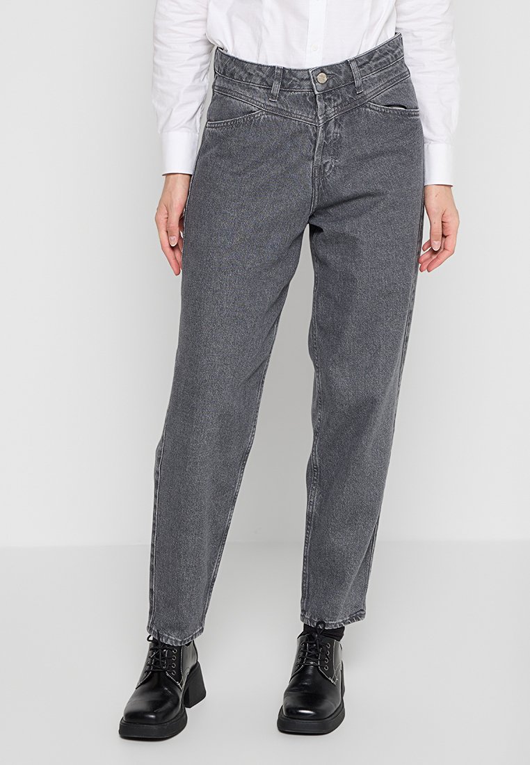 Jeans in denim grigio con vita alta, taglio dritto e tasche sul davanti cucite, abbinati a stivali neri con lacci.