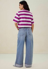  Paarse en witte gestreepte cropped t-shirt gecombineerd met lichtblauwe wijde denim jeans, met een hoge taille en opgerolde boorden.