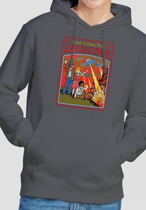 Three children on grass point at flying saucers firing beams causing explosions under the text "Here Comes The Apocalypse."