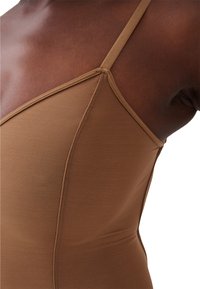 Bruine bodysuit met dunne bandjes, met een getailleerd ontwerp en een zachte textuur. Stikseldetails zijn zichtbaar langs de naden.