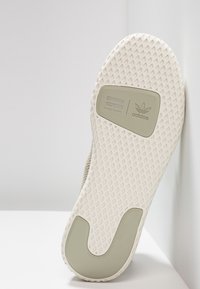 Světlá šedá podrážka tenisky s texturovaným bílým gumovým povrchem, s vyraženým logem a zakřiveným akcentem na okraji.