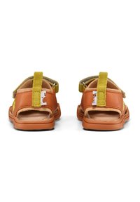 Sandalias de dedo en cuero naranja con acentos amarillos. Presenta correas ajustables, suela acolchada y un talón con lazo para facilitar el uso.