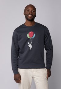Donkerblauwe sweatshirt met een afbeelding van een astronaut die kleurrijke ballonnen vasthoudt. Heeft lange mouwen en een ronde halslijn, gemaakt van zacht materiaal.