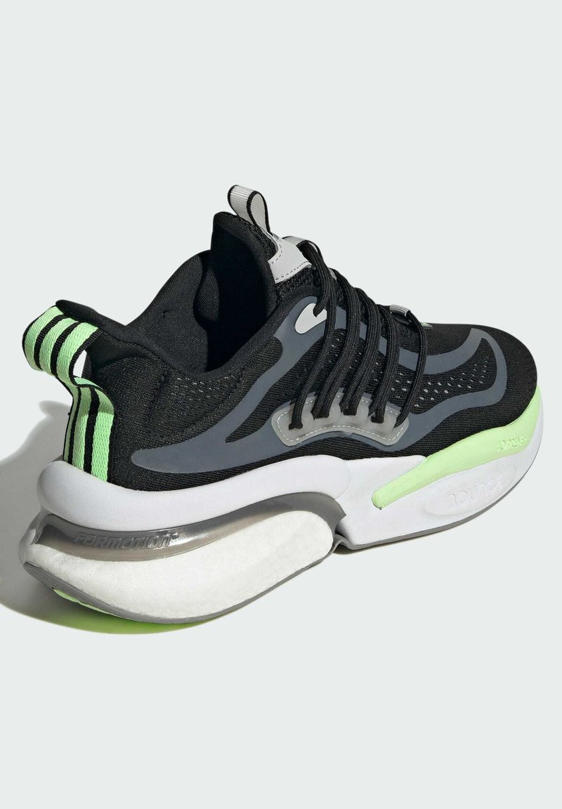 Chaussure de sport noire avec une tige texturée, des accents gris, des touches de vert et une semelle blanche épaisse dotée d'une technologie d'amortissement.