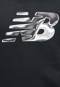 Μαύρο φούτερ από ύφασμα με γυαλιστερό, ασημί λογότυπο New Balance που διαθέτει δυναμικά, ρευστά στοιχεία και υφασμένη επιφάνεια.