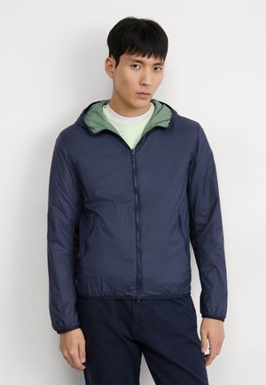 Giacca leggera blu navy con cappuccio, dotata di foderatura verde, chiusura con zip e tasche laterali. Tessuto liscio e resistente all'acqua.
