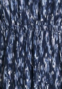 Blå och vit abstrakt tyg med penseldrag mönster, med horisontell söm och rynkade veck nedanför midjan.