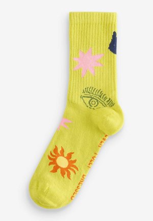 Geltoni raukšlėti kojinės su spalvingais raštais: rožinės žvaigždės, oranžinė saulė ir akies motyvas. Pagamintos iš švelnios, tamprios medžiagos.