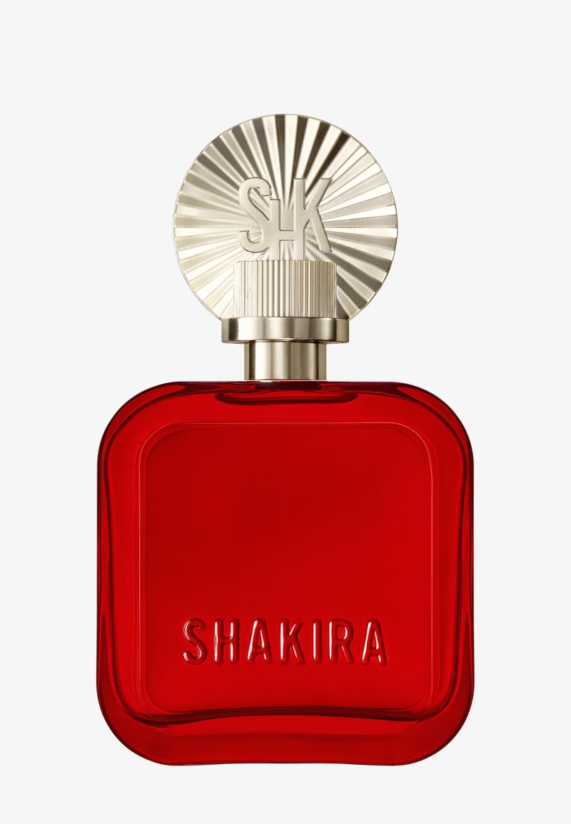 Rød firkantet parfume flaske med guld cirkulært låg præget med "SK" og "SHAKIRA" på forsiden af flasken.