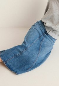 Džínová sukně s širokým, rozšířeným střihem a viditelnými švy. Světle modrá barva, vyrobena z měkké bavlněné tkaniny. Neformální design.