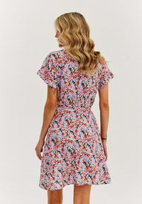 Kwiatowa sukienka z wielokolorowym wzorem na jasnym tle, krótki, falbaniasty rękaw i dopasowana talia z rozszerzanym dołem.