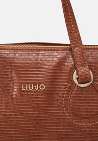 Braune, strukturierte, synthetische Handtasche mit goldfarbenen Beschlägen, geprägt mit dem Markenschriftzug "LIU JO" und Reißverschluss. Die Griffe sind für Langlebigkeit vernäht.