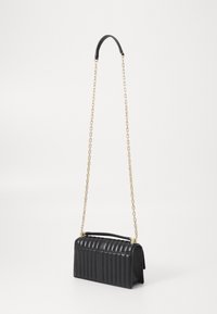 Black leather handbag with vertical quilted texture, gold chain strap, rigid rectangular shape, and a small top handle.