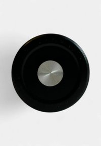 Schwarzer runder Knopf mit einem silbernen metallischen Zentrum, von oben auf einem weißen Hintergrund betrachtet.