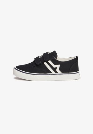 Chaussure noire en toile avec semelle extérieure en caoutchouc blanc, dotée de deux bandes Velcro et d'accents en zigzag blanc contrastant sur le côté.