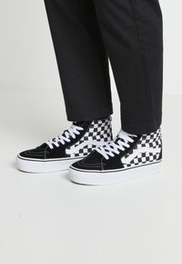 Schwarz-weiße kariertete High-Top-Sneaker aus Wildleder mit weißen Schnürsenkeln und einer dicken weißen Gummisohle. Ausgestattet mit Kontrastnähten.
