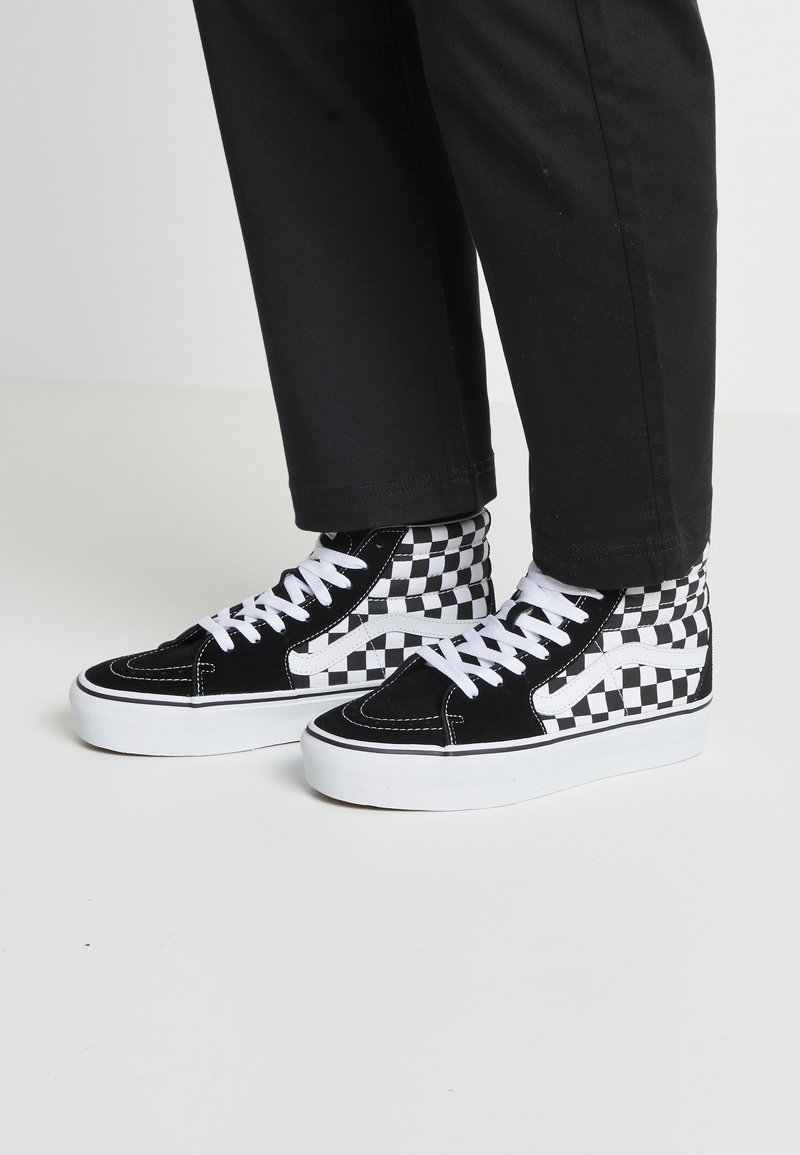 Schwarz-weiße kariertete High-Top-Sneaker aus Wildleder mit weißen Schnürsenkeln und einer dicken weißen Gummisohle. Ausgestattet mit Kontrastnähten.