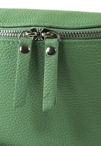 Groen gestructureerde leren tas met een bovenste ritssluiting, voorzien van twee leren trekkerhandvatten en zilverkleurige hardware accenten, met een korrelige afwerking.