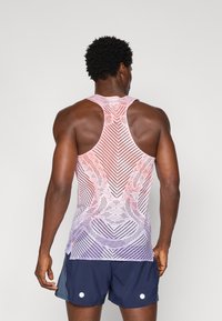Tanktop gemaakt van ademend materiaal, met een verlooppatroon van rode naar paarse tinten en een racerback ontwerp. Gecombineerd met marineblauwe shorts.