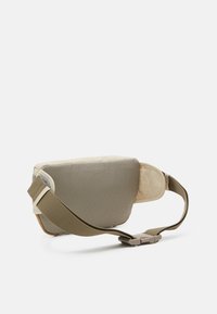 Khaki schoudertas met een textuurovervlak, beige accenten, een verstelbare schouderband en een snelontgrendelingssluiting. Compacte en rechthoekige vorm.
