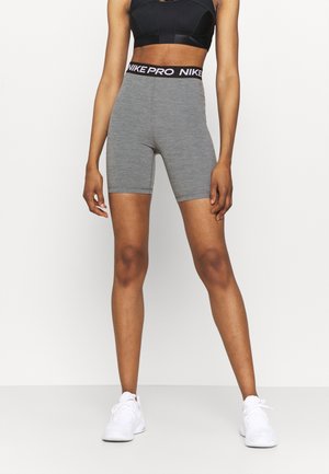 Shorts de sport gris au design ajusté, avec un logo NIKE PRO sur la ceinture élastique noire et un tissu lisse et extensible.
