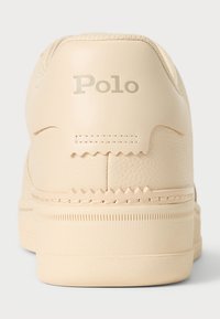 Beige sneakers med en texturerad läderfinish och en sydd sula. Har upphöjd "Polo"-logga på hälen och zigzagdetalj på ovandelen.