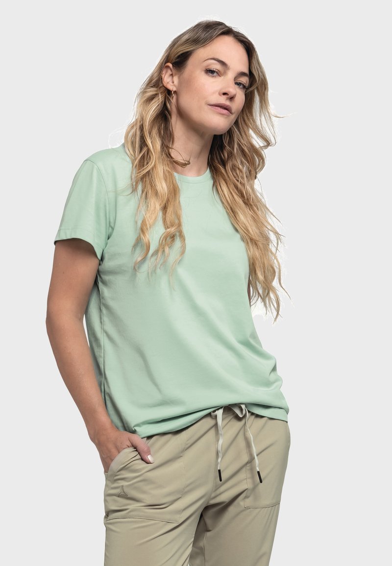 Hellgrünes Baumwoll-T-Shirt mit rundem Ausschnitt und kurzen Ärmeln, kombiniert mit beigen Hosen mit Kordelzugdetails und Taschen.