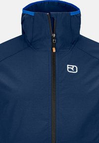 Navy blue jacket with a high collar, front zipper, and white logo. Features smooth fabric texture and contrasting blue accents on the collar.