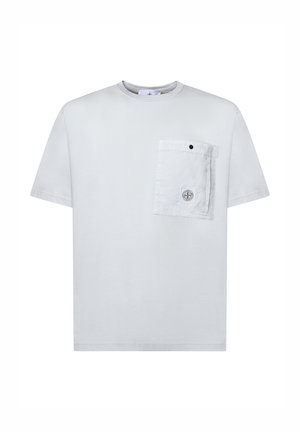 Camiseta blanca de manga corta con un gran bolsillo cuadrado en el pecho que presenta un pequeño logo circular y un botón negro de presión.