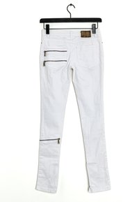 Bílé úzké džíny z bavlny se dvěma zadními kapsami, dvěma kapsami na stehnech se zipem a malým zipovým detailem na kotníku.