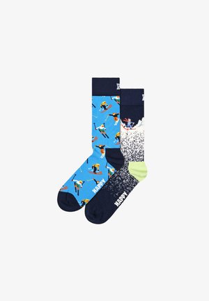 Blue and navy socks featuring colorful skiing figures, textured patterns, and logo detail. One sock has a green accent and splatter design.
