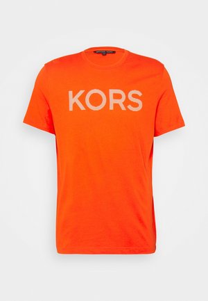 T-shirt orange à manches courtes et col rond avec le texte "KORS" rayé en blanc centré sur le devant et une étiquette Michael Kors noire à l'intérieur du col.