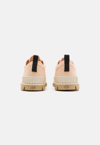 Sneakers in tela rosa chiaro con suola in gomma beige, texture rigata e un linguetta nera sul tallone per facilitarne l'indossamento.