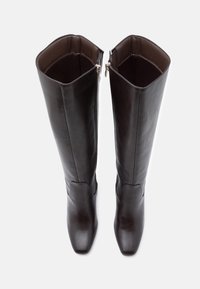 Καφέ δερμάτινες μπότες μέχρι το γόνατο με λείο φινίρισμα, στρογγυλή μύτη και πλαϊνούς φερμουάρ. Σχεδιασμένες για εφαρμοστή σιλουέτα.