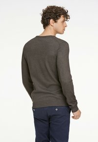 Mörkgrå långärmad stickad tröja med rund halsringning, åtsittande manschetter och en jämn textur, som bärs med marinblå byxor.