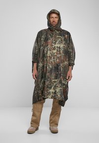 Camouflage poncho dalam nuansa hijau, coklat, dan hitam, dilengkapi dengan penutup kepala dan potongan longgar. Bahan ringan dengan tekstur tahan air.