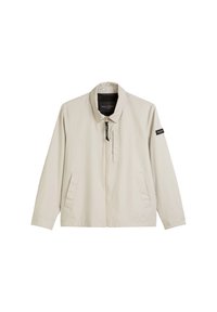 Light beige jacket with a stand collar, front zip closure, two side pockets, and a black logo patch on the left sleeve. Smooth fabric texture.