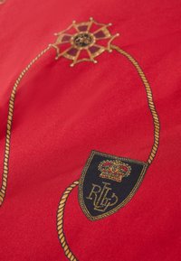 Rdeča tkanina z zlatimi vezeninami. Oblikovanje ladijskega kolesa in vrvi se prepleta s ščitom, ki nosi krono in inicialke "R" in "L."