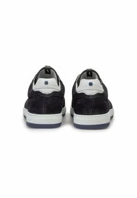 Dunkelblaue Wildlederschuhe mit weißen texturierten Akzenten, kontrastierenden weißen und grauen Sohlen, ausgestattet mit einem kleinen Logodetail an der Ferse.