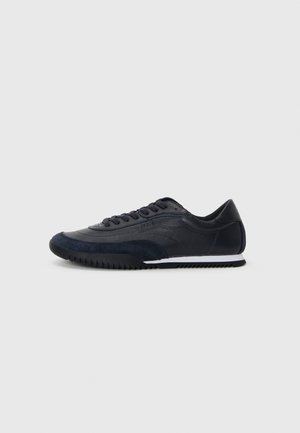 Marineblaue Sportschuhe mit einem Obermaterial aus Leder und Wildleder, runder Zehenform, Schnürverschluss, strukturiertem Laufsohle und kontrastierender weißer Sohle.