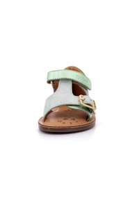Sandalias verde menta con una correa con hebilla, contraste de materiales de ante y brillante, diseño de punta abierta y una plantilla ligeramente texturizada.