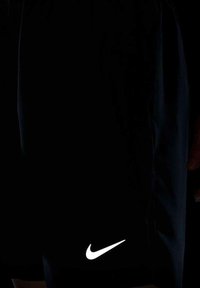 Czarne krótkie spodenki sportowe Nike wykonane z gładkiego materiału, z wyróżniającym się białym logo na dolnym brzegu. Prosty design, bez dodatkowych wzorów.